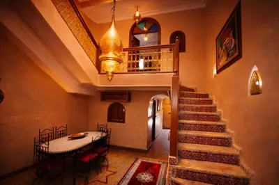 a hallway with a staircase with a table and a chandelier at Riad 16 Dar and Pool in Marrakech