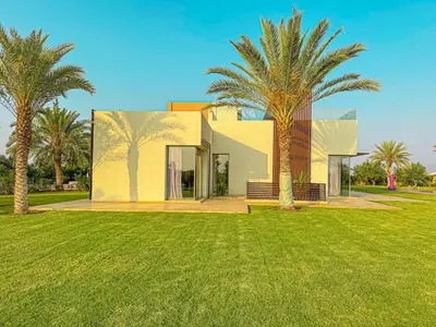 a house with palm trees in front of a yard at Private Mountain View Oasis in Bou Azza