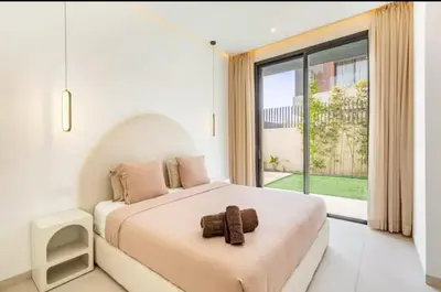a white bedroom with a large bed and a large window at Kais in El Rhechat