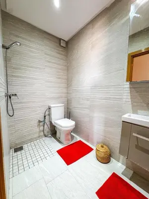 a bathroom with a toilet and a shower and red mats at Appartement de luxe Marrakech - Targa in Marrakech