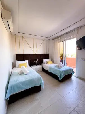 a bedroom with two beds and a large window at Appartement de luxe Marrakech - Targa in Marrakech