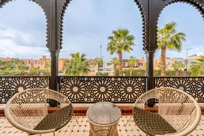 three chairs and a table on a balcony with palm trees at Andalusian Dream Villa pool and balcony in Marrakech