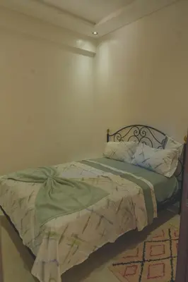a bed in a room with a white wall at Spacious Apartment with AC & Fast WiFi 5 Guests in Marrakech