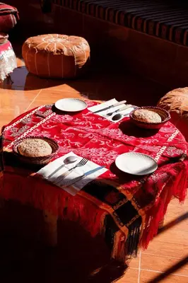 a table with plates and silverware on a red table cloth at Berber House Authentic Moroccan Farm Stay in El Rhechat