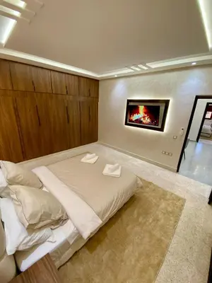 a bedroom with a large bed with a fireplace at Charmant cocon moderne in Marrakech