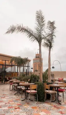 a restaurant with tables and chairs and palm trees at Penthouse city center asdfghjsasdfghjk in Marrakech