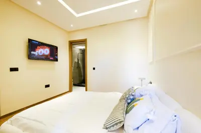 a bedroom with a white bed with a tv on the wall at Appartement vacances famille Marrakech in Marrakech