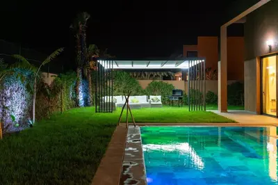 a swimming pool in the yard of a house at night at Luxury Villa with Breakfast & Padel Access in Marrakech