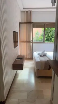 a bedroom with a bed and a table and a window at Location Centrale - Heated 1BR - Parking - Netflix in Marrakech