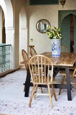a wooden table with chairs and a vase with a plant at Riad Johara Marrakech in Marrakech
