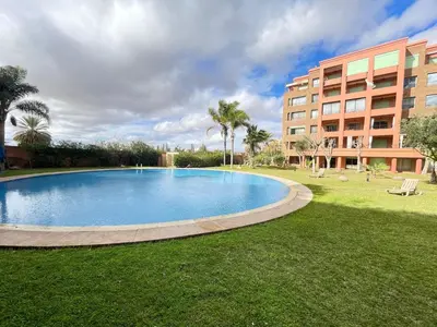 a large swimming pool in a park next to a building at nice apartment, Luxury Wintering, Caprice Palace in Marrakech
