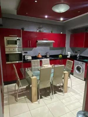 a kitchen with red cabinets and a table and chairs at Appartement Nomade in Marrakech