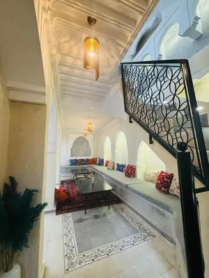 a living room with a staircase and a table at Riad l'Oasis Bleue en privatisation 10 pers 3 jours mini in Marrakech