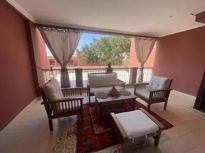 a living room with a table and chairs and a balcony at Résidence Soltana in Marrakech