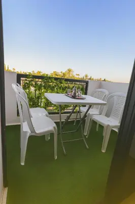 a table and chairs on a balcony with green flooring at Modern apartment with Atlas view in Marrakech