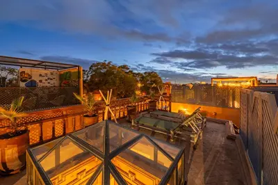 a balcony with a glass table on a roof at Riad Lalla Rachida in Medina Heart Of Marrakech B&B in Marrakech