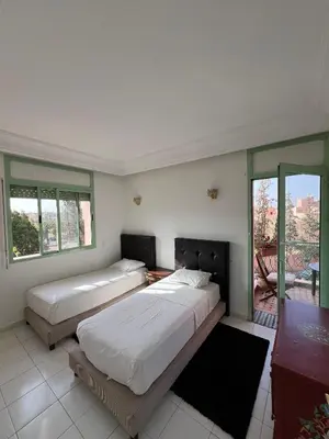 a bedroom with two beds and a balcony at Marakech Giliz Atlas in Marrakech