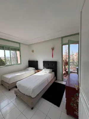 two beds in a room with windows at Marakech Giliz Atlas in Marrakech