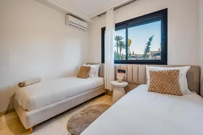 two beds and a couch in a room with a window at Grand duplex 4 ch - Piscine - Marrakech in Marrakech
