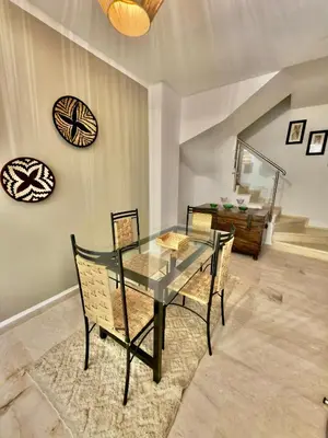 a dining room with a glass table and chairs at Charmant Duplex 2BR - quartier Hivernage - Piscine in Marrakech