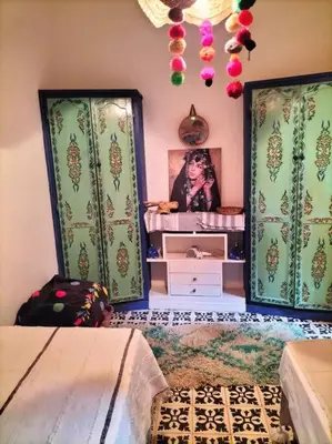 a room with two beds and a dresser with a picture at Dar tranquille in Marrakech