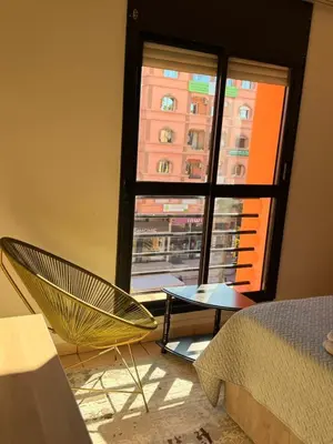 a room with a bed and a window and a chair at Tay Home in Marrakech