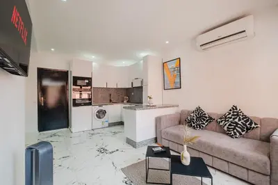 a living room with a couch and a kitchen at Modern & Cozy Apartment 2 min Carré Eden Guéliz in Marrakech