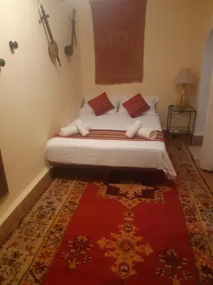 a bed in a room with a red rug at Riad ICA in Marrakech