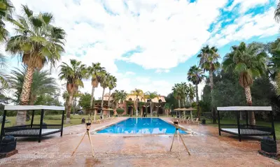 a pool at a resort with palm trees at Royal Moroccan House in Marrakech