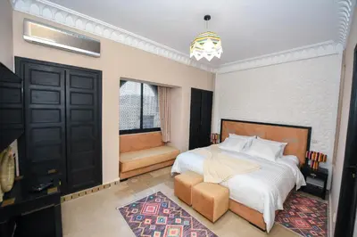 a bedroom with a bed and a chair and a window at Royal Moroccan House in Marrakech