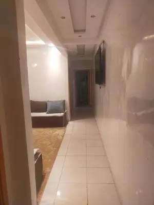 a hallway with a couch and a tv on a wall at appartement pour famille ou femme in Marrakech