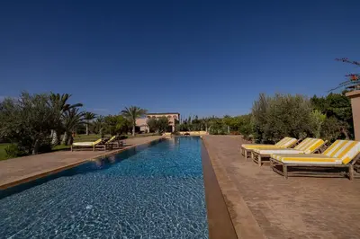 a swimming pool with lounge chairs next to a resort at Villa Yemna - Villa signature Paddle Marrakech in Segraga