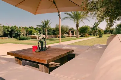 a wooden table with a vase on it with an umbrella at Villa Yemna - Villa signature Paddle Marrakech in Segraga