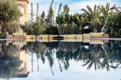a swimming pool with yellow and white pillows and trees at Villa Yemna - Villa signature Paddle Marrakech in Segraga
