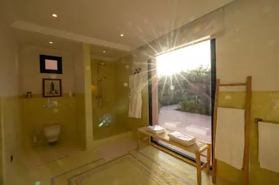 a bathroom with a shower and a toilet and a window at Villa Yemna - Villa signature Paddle Marrakech in Segraga