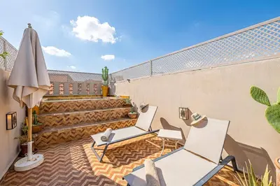 a patio with two chairs and an umbrella and stairs at Riad Kenous - Exclusive&New -6 pax- Pool & Breakfast in Marrakech