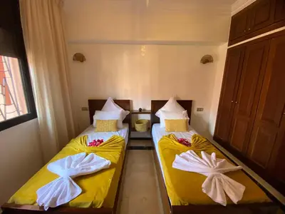 two beds in a small room with yellow sheets at appartment L'Hivernage in Marrakech