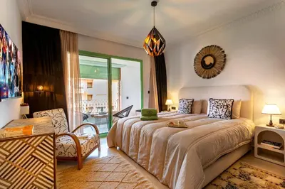 a bedroom with a bed and a chair and a mirror at Appartement idéal a l'hivernage in Marrakech