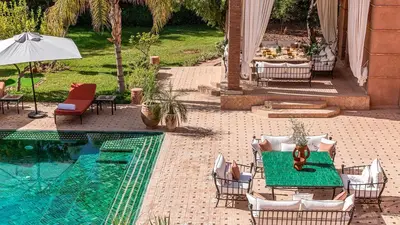 a patio with a table and chairs next to a pool at Villa Rehame in Oulad Jellal