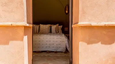 a bed is seen through an open doorway at Villa Rehame in Oulad Jellal