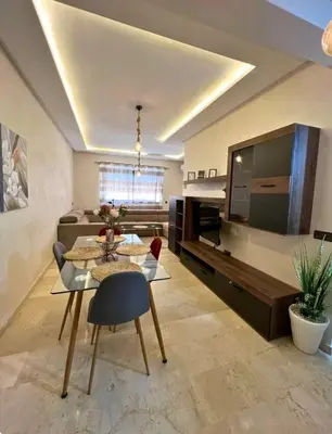 a living room with a dining table and a large tv at Le lux de gueliz in Marrakech