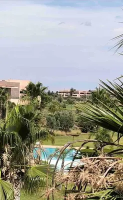 a view of a swimming pool with palm trees at Super 3-bedroom living room with view of Prestigia Golf Pools in Marrakech