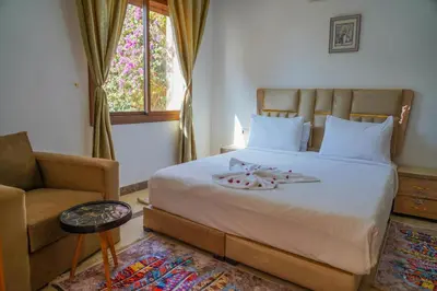 a bedroom with a bed and a chair and a window at فيلال نادية in Marrakech