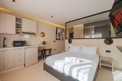 a bedroom with a large white bed and a kitchen at Studio elegant raffine pour un sejour tout confort in Marrakech