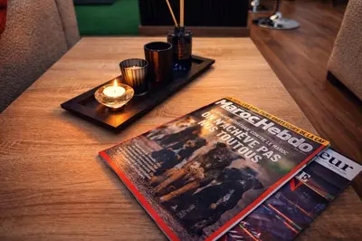 a magazine on a table with a candle and a book at Studio sur guiliz avec piscine et parking in Marrakech