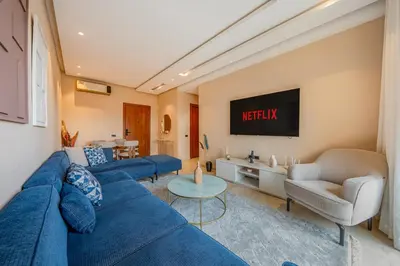 a living room with blue couches and a tv at Prestigia Jubaea Apartment Green Escape & Pool in Marrakech