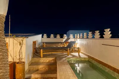 a balcony with two benches and a swimming pool at night at Riad Imani-Gorgeous Sunny Terrace Breakfast Pool in Marrakech