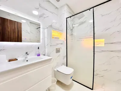 a white bathroom with a shower and a toilet at Elegant apartment with pool, highly desirable area in Marrakech
