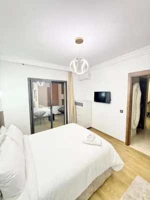 a white bedroom with a bed and a mirror at Elegant apartment with pool, highly desirable area in Marrakech