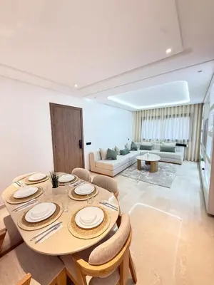 a dining room with a table and chairs and a living room at Apartment with pool & gym in Marrakech